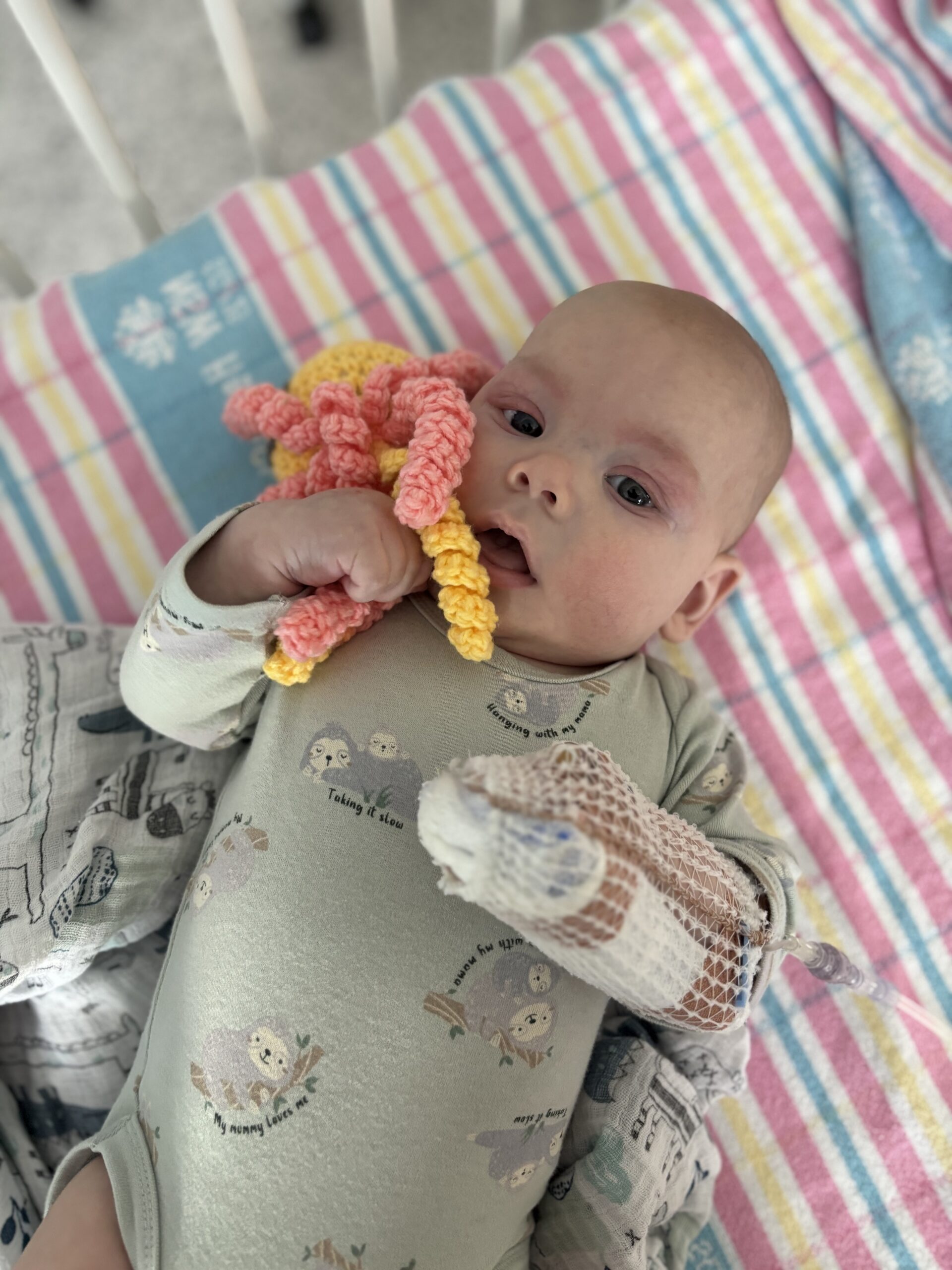 Baby clutching a crocheted octopus plush toy from the Ronald McDonald House Charities Greater Western Sydney Hospitality Cart at Campbelltown Hospital