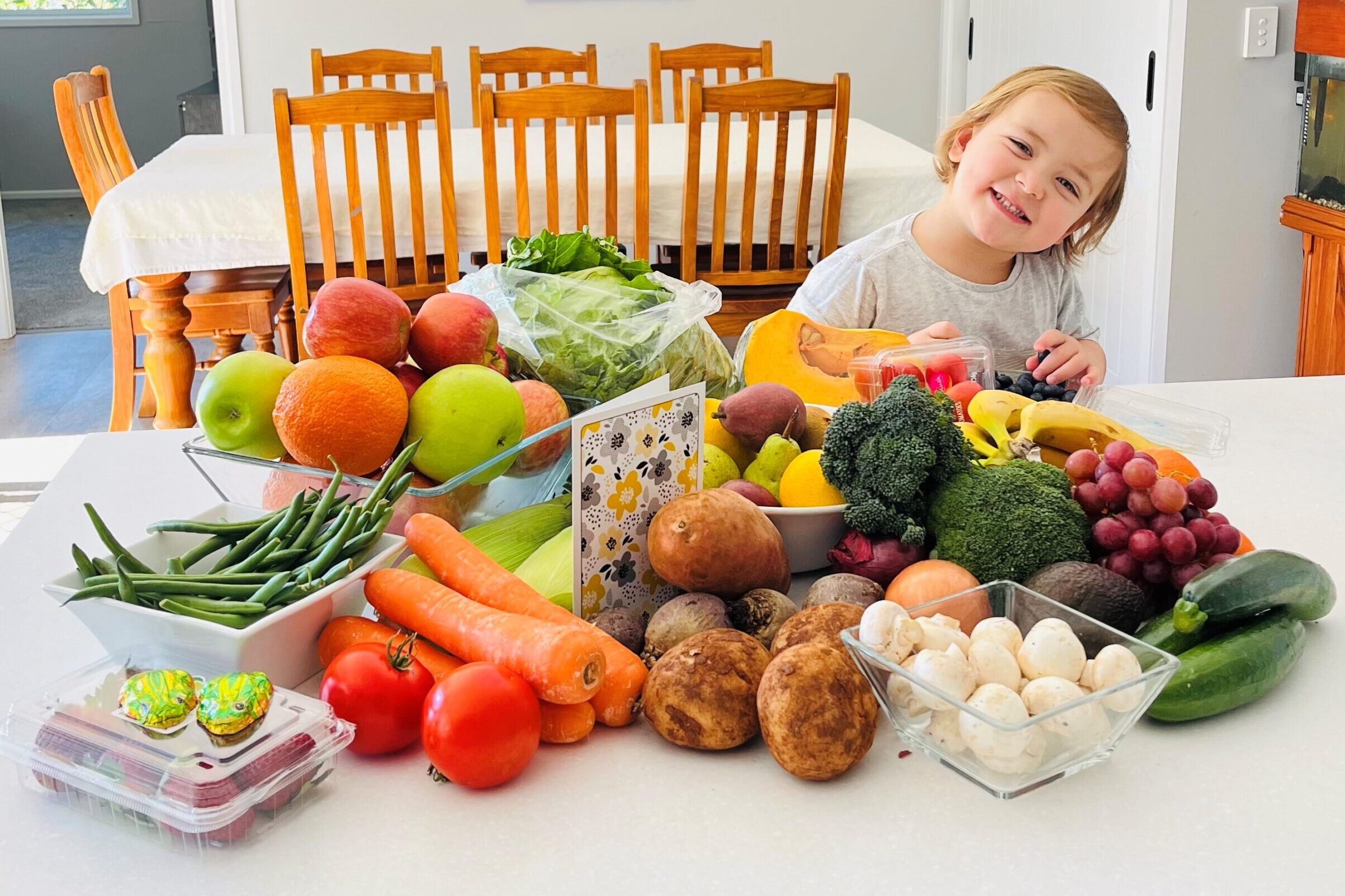 Child smiling at a fruit and vegetables delivery for their family, part of the Families on the Move program by Ronald McDonald House Charities Greater Western Sydney